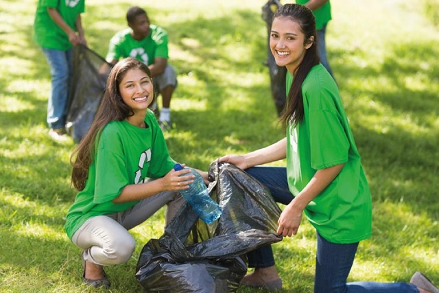 Niñas recogiendo basura en un parque para cuidar el medio ambiente
