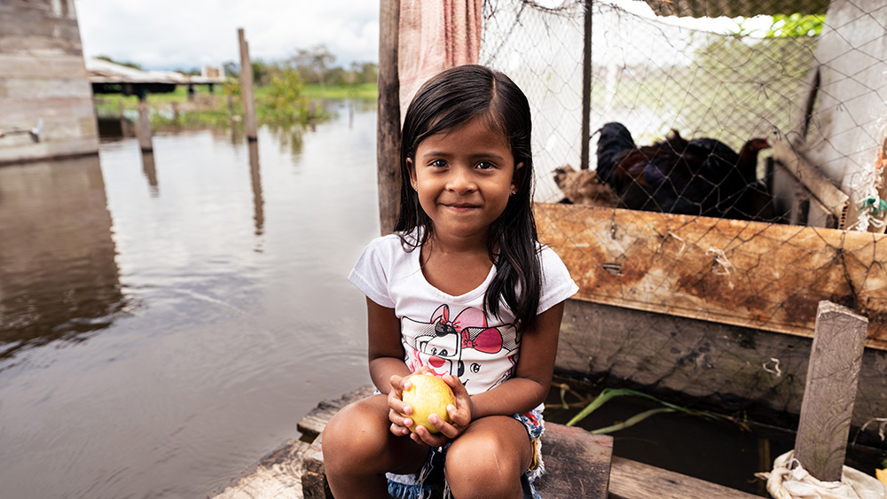Una niña en el río Amazonas sonríe feliz.