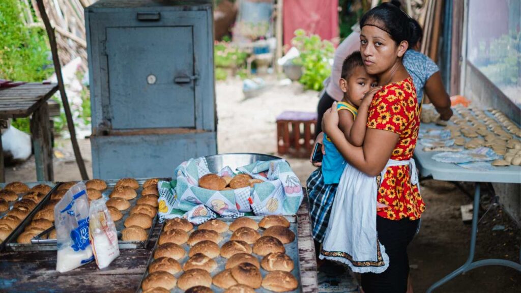 Madre abrazando a su hijo y preparando comida para combatir las causas de la desnutrición en su comunidad