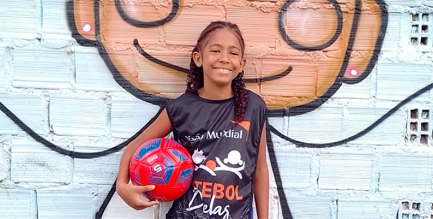 Josi posa con una pelota y una camiseta del proyecto Futebol Delas.